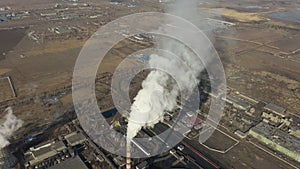 Aerial view of thermal power plant. Drone flies over chimney smoke pipes and cooling towers of industrial area on sunset