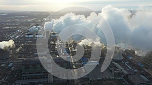 Aerial view of thermal power plant. Drone flies over chimney smoke pipes and cooling towers of industrial area on sunset