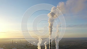 Aerial view of thermal power plant. Drone flies over chimney smoke pipes and cooling towers of industrial area on sunset