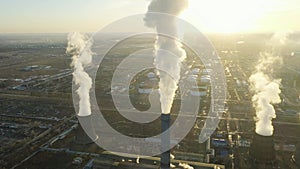 Aerial view of thermal power plant. Drone flies over chimney smoke pipes and cooling towers of industrial area on sunset