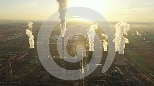 Aerial view of thermal power plant. Drone flies over chimney smoke pipes and cooling towers of industrial area on sunset