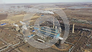 Aerial view of thermal power plant. Drone flies over chimney smoke pipes and cooling towers of industrial area on sunset