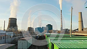 Aerial view of thermal power plant. Drone flies over chimney smoke pipes and cooling towers of industrial area on sunset