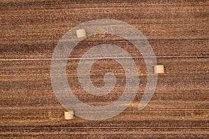 Aerial view of three bales of straw in a grain field after harvest seen directly from above