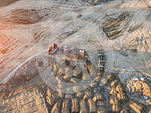 Aerial view of three multi-colored dump tip trucks unloading in