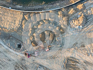 Aerial view of three multi-colored dump tip trucks unloading in