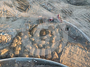 Aerial view of three multi-colored dump tip trucks unloading in