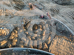 Aerial view of three multi-colored dump tip trucks unloading in