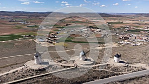 Aerial view of three traditional windmills in a row in Consuegra in Toledo, Spain, with agricultural fields in the background