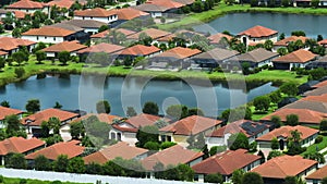 Aerial view of tightly packed homes in Florida closed living clubs with lake water in the middle. Family houses as