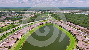 Aerial view of tightly packed homes in Florida closed living clubs with lake water in the middle. Family houses as