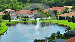 Aerial view of tightly packed homes in Florida closed living clubs with lake water in the middle. Family houses as