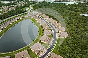 Aerial view of tightly packed homes in Florida closed living clubs with lake water in the middle. Family houses as