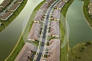 Aerial view of tightly packed homes in Florida closed living clubs with lake water in the middle. Family houses as