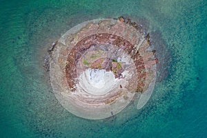Aerial view of tiny rocky island in sea