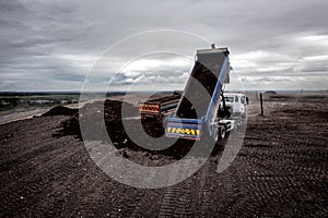 Aerial view of a tipper truck with raised trailer on a household waste landfill dump