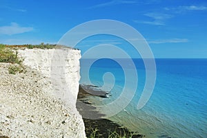 Aerial view to blue turquoise water of English channel and a little white sailboat at the background and white chalk stones of cli