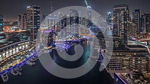 Aerial view to Dubai marina skyscrapers around canal with floating boats night timelapse