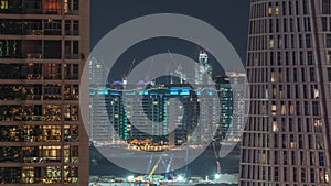 Aerial view to Dubai marina skyscrapers with construction site and Palm Jumeirah Island on background night timelapse.