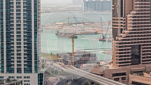 Aerial view to Dubai marina skyscrapers with construction site and Palm Jumeirah Island on background timelapse.