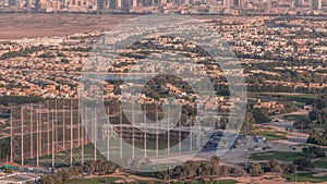 Aerial view to Golf course with green lawn and lakes, villa houses behind it timelapse.