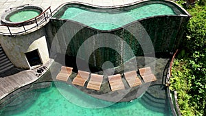 Aerial view to infinity hotel pool in luxury hotel resort. Luxury round pool with white umbrellas and sun beds in