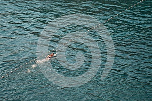 Aerial view to a man swimming in a sea along safety buoys