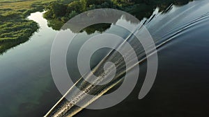 Aerial view to motorboat on calm water at morning light