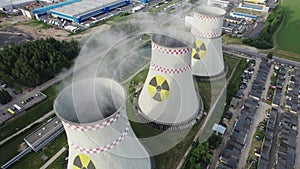 Aerial view to nuclear power plant. Nuclear power plant cooling towers with a radiation symbol emit steam. Power