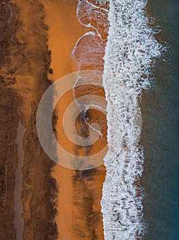 Aerial view to ocean waves and red sand beach