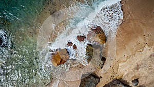 Aerial view top seashore, rocky coast, waves crashing on rock cliff. Blue ocean surface sunny summer