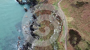 Aerial view top down shot of sea shore,stony rocks and giant cliffs with breaking ocean waves in ireland