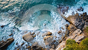 Aerial view top seashore, rocky coast, waves crashing on rock cliff. Blue ocean surface sunny summer