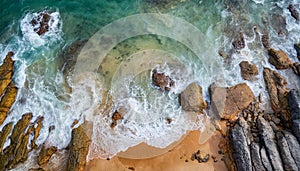 Aerial view top seashore, rocky coast, waves crashing on rock cliff. Blue ocean surface sunny summer