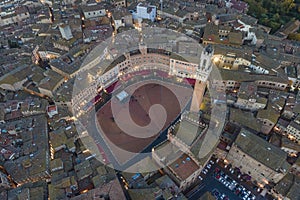 Aerial view of Torre del Mangia with city skyline at sunset, a famous landmark in Piazza del Campo, Siena, Tuscany, Italy