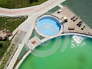 Aerial view of a tourist recreation center with a children`s pool with blue clear water, an inflatable slide and wooden sun