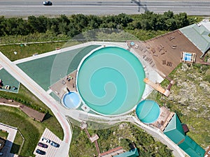 Aerial view of a tourist recreation center in with three swimming pools and wooden sun loungers on nature in the Altai mountains