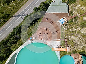 Aerial view of a tourist recreation center in with two swimming pools and wooden sun loungers on nature in the Altai mountains on