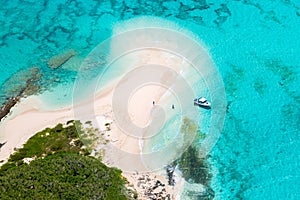 Aerial view of tourists, jet boat, idyllic empty sandy beach, remote island, azure turquoise blue lagoon, New Caledonia, Oceania.
