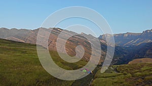 Aerial view of tourists who wake up and meet the sunrise on rock in Dagestan. Red car and tents against the backdrop of