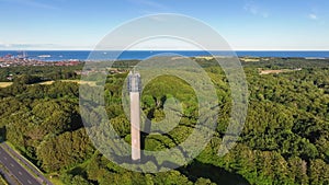 An aerial view of a  tower built in a wooded area on a sunny summer evening.