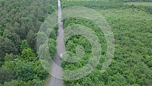 aerial view tracking after car moving by speedway green forest by both side