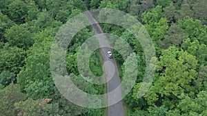 aerial view tracking after car moving by speedway green forest by both side