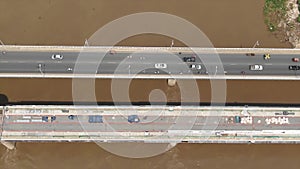 Aerial view tracking left to right over bridge construction with muddy river seen passing beneath