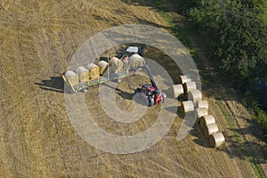 Aerial view of tractor collecting straw bales