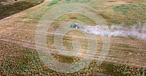 aerial view on tractor cultivator or seeder plows the land, prepares for crops. dust on field