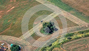 Aerial View of a tractor cutting the green grass field in a farm.