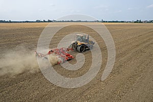 Aerial view of a tractor on dusty plowed field