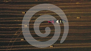 Aerial view of tractor with hay in the field. Bales of hay stacked in the trailer. Agricultural work.