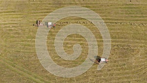 Aerial view of tractor with hay in the field. Bales of hay stacked in the trailer. Agricultural work. The concept of